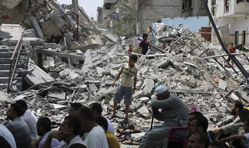 Palestinos rezam perto de ruínas de mesquita na Faixa de Gaza na sexta-feira (15) (