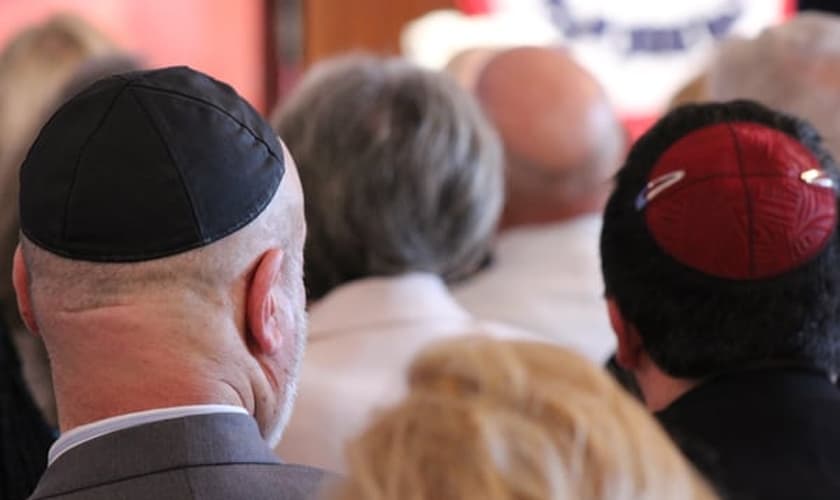 Judeus reunidos em uma sinagoga, utilizando seus quipás sobre a cabeça.