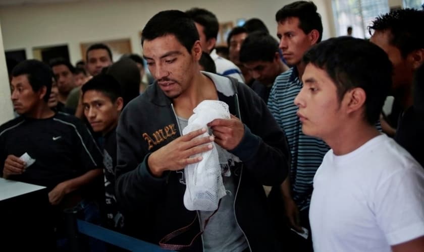 Imigrantes ilegais aguardam enquanto recebem seus pertences e processam sua volta ao aeroporte de La Aurora (Guatemala), de onde saíram.