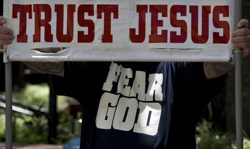 "Confie em Jesus", afirma cartaz, em inglês, durante ação de evangelismo. (Foto: Reuters)