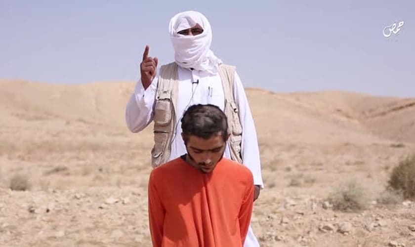Um extremista do EI, vestido de branco, explica que sua morte é uma espécie de punição. (Foto: Heavy)