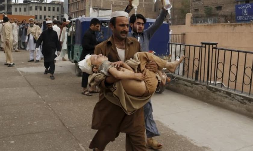 Homem carrega garoto ferido, após o terremoto, em Peshawar, no Paquistão (Foto: Reuters)