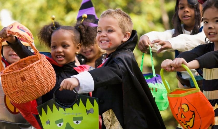 Crianças estendem suas sacolas para ganhar doces, durante festas do Halloween.