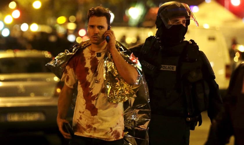 Policial acompanha vítima do ataque à casa de shows 'Bataclan', em Paris. (Foto: Reuters)