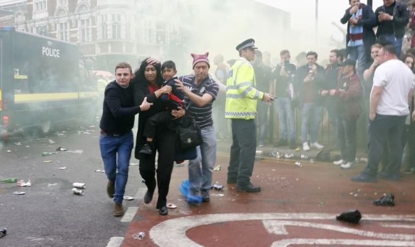 Imagem registrou momento em que Paul Sanderson (à direita) e outro homem ajudaram mãe e filho a fugir do tumulto gerado por torcedores antes de um jogo de futebol na Inglaterra. (Foto: Reuters)
