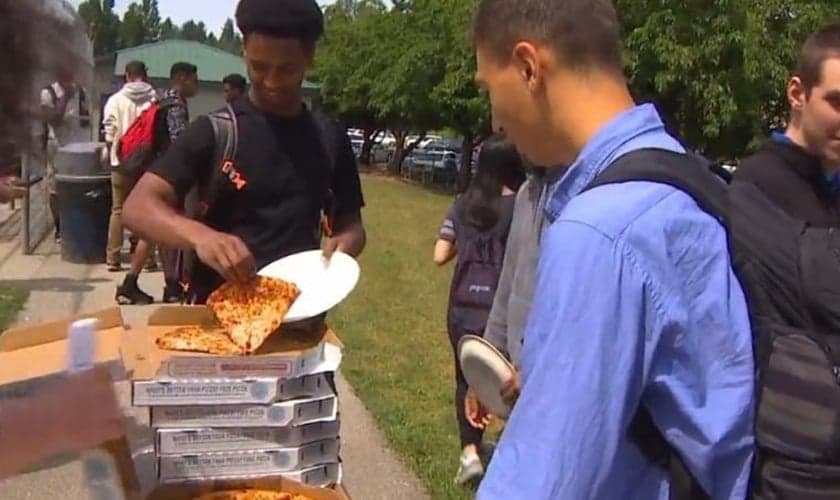 Estudante pega um pedaço de pizza grátis entregue pela igreja Bethany Community Church em Seattle, nos EUA. (Foto: Reprodução/Komo TV)