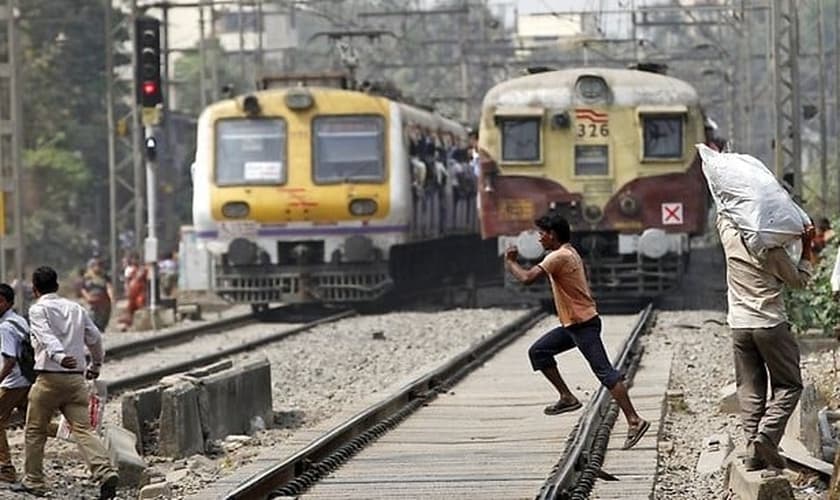 Imagem ilustrativa. Jovem atravessa trilho diante de um trem em funcionamento, em Mumbai, na Índia. (Foto: Reprodução)