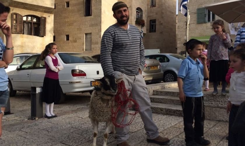 Homem segura cordeiro separado para simulação de sacrifício de Páscoa. (Foto: Times Of Israel)