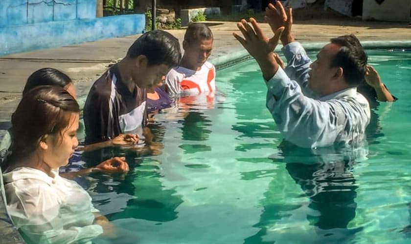 Pastor faz oração durante batismo de novos convertidos, em país da Ásia. (Foto: Christian Aid Mission)