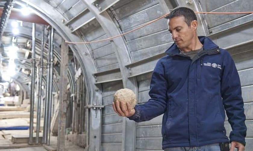 Arqueólogo segura bola de pedra, usada na batalha por Jerusalém, em 70 d.C. (Foto: IAA)