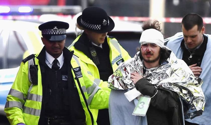 Policiais britânicos socorrem homem ferido em ataque, em Londres. (Foto: El País)
