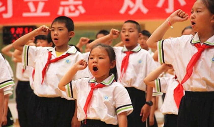 'Jovens Pioneiros' em uma escola primária na região autônoma de Ningxia Hui fazem um juramento durante uma atividade do evento "O Lenço Vermelho Segue a Festa" no Dia das Crianças. (Foto: Bitter Winter)