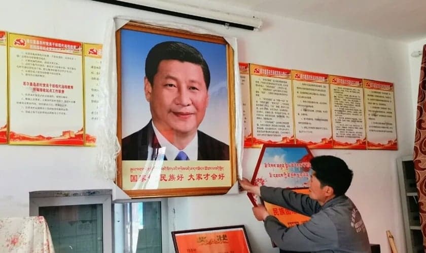 Homem pendura um retrato do presidente chinês Xi Jinping, no condado de Dzoge, no leste do Tibete. (Foto: Free Tibet)