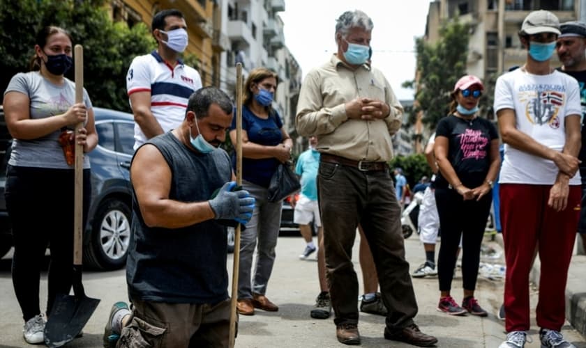 Voluntários se unem em mutirão para limpeza das ruas de Beirute e param para orar pelo Líbano. (Foto: AFP)
