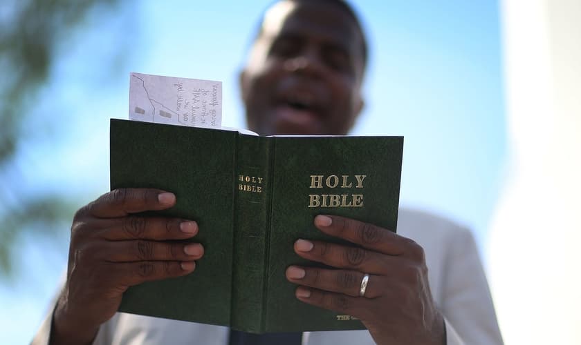 Pastor lê a Bíblia enquanto conduz uma oração, nos EUA. (Foto: Joe Raedle/Getty Images)