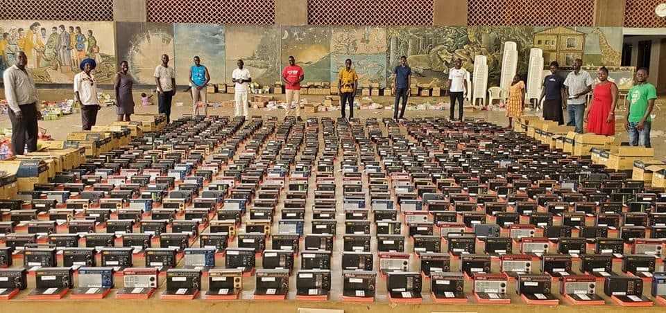 Uma equipe da Fundação Irene Gleeson, em Uganda, ora diante de Bíblias, rádios transistorizados que devem ser distribuídos a 1000 famílias nos distritos de Kitgum e Lamwo. (Foto: Reprodução/UGCN).