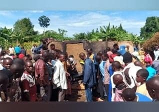 Moradores reunidos em frente à casa queimada do pastor Mukisa. (Foto: Morning Star News).