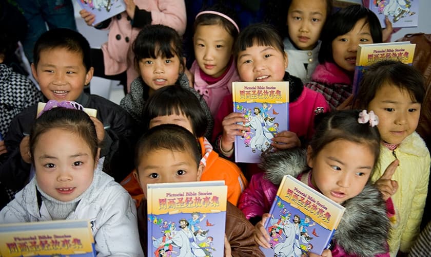 Crianças recebem literatura cristã infantil, distribuída por missionários, na China. (Foto: American Bible Society News)