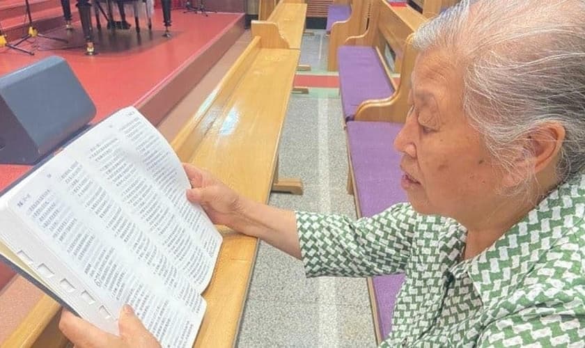 Zheng Yuzhen lendo sua Bíblia nova. (Foto: Reprodução/Bible Society/UBS-CP)