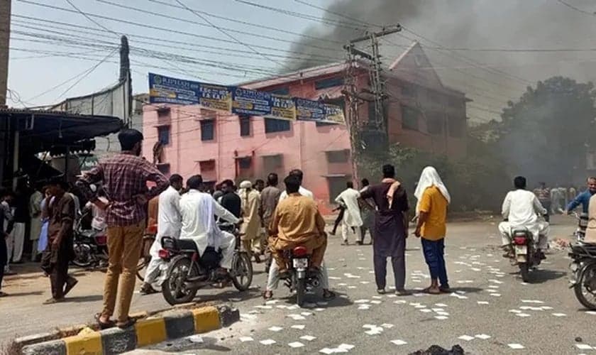 Uma multidão observa a fumaça subir de uma igreja incendiada em Jaranwala, Paquistão, em 16 de agosto de 2023. (Foto: Daud Irshad)