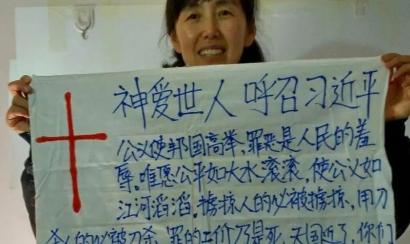 Zhou Jinxia segurando cartaz com mensagem direcionada a Xi Jinping. (Foto: ChinaAid)