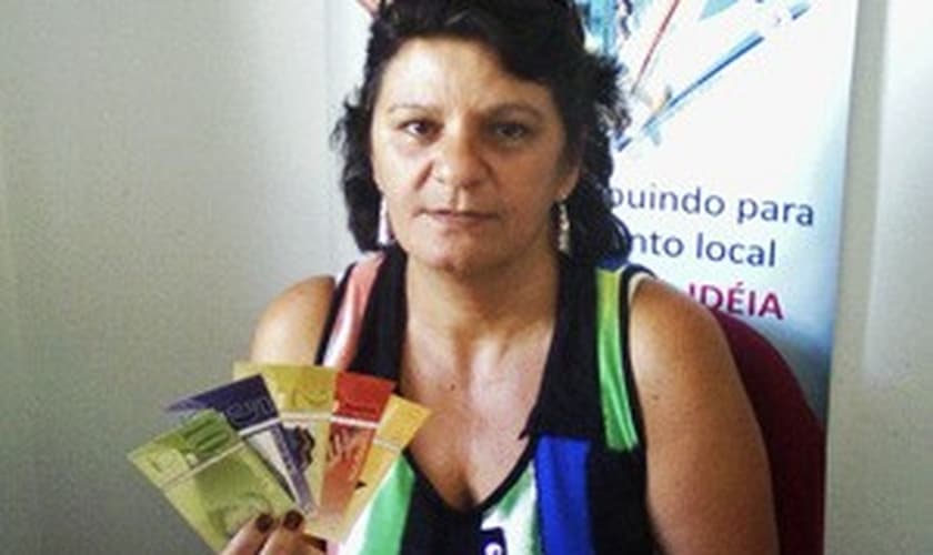 Maria Vani segura as notas de 'Comissari' no banco comunitário