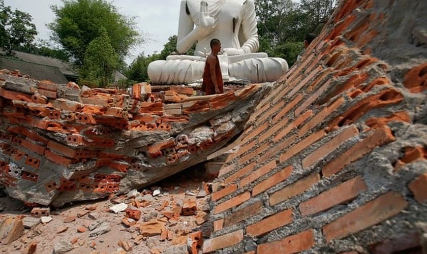 Budista caminha sobre escombros de terremoto em templo na Tailândia.