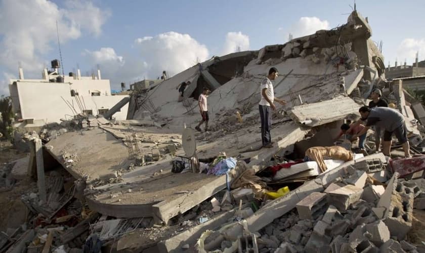 Palestinos tentam recuperar bens de um edifício destruído em um ataque israelense em Beit Lahya, norte da Faixa de Gaza
