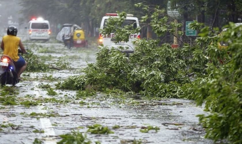 Veículo atravessa estrada repleto de pedaços de árvores que caíram em Manila, nas Filipinas