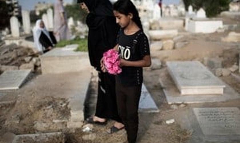Mulher palestina e menina levam flores em um túmulo da família no feriado do fim do Ramadã (Eid al-Fitr) em Gaza. (