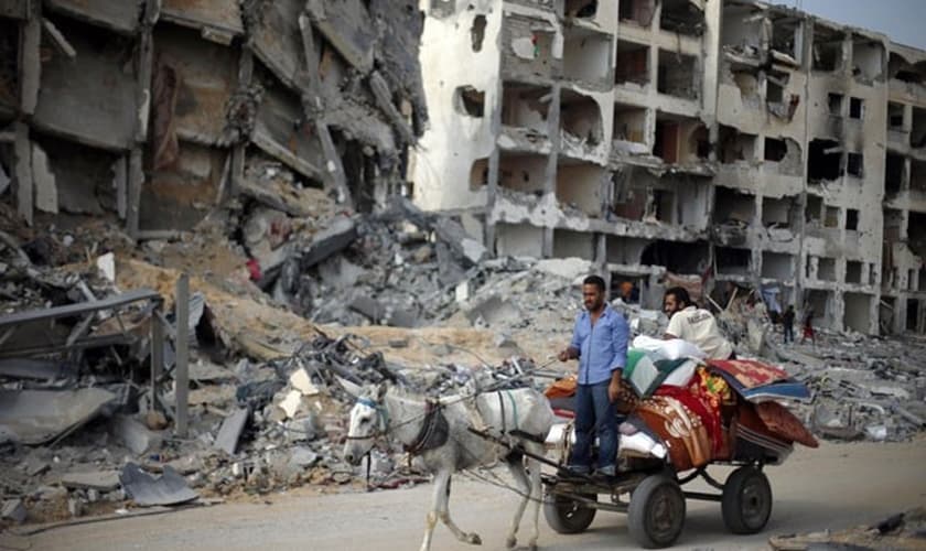Palestinos passam por prédio destruído ao voltar para Beit Lahiya nesta quarta-feira (6)
