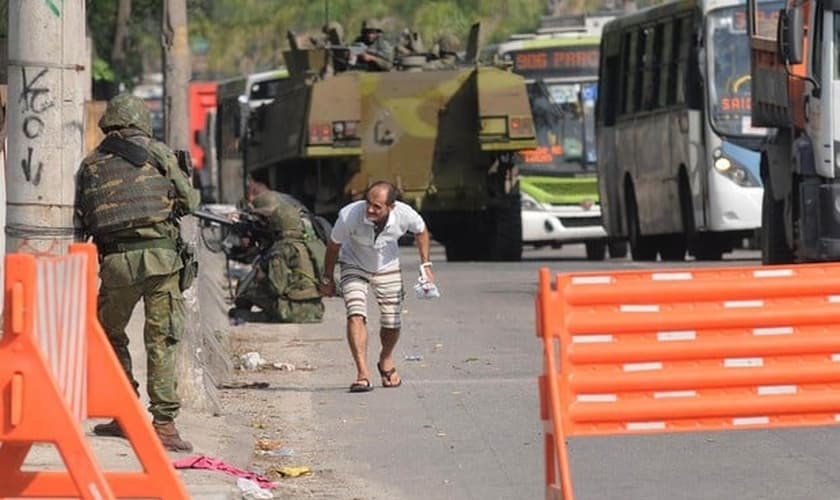 Homem se abaixa com medo de tiros na Avenida Brasil, no Rio de Janeiro, após o início de um tiroteio na altura da Fiocruz, na Zona Norte da cidade. A via foi fechada na tarde desta quarta-feira (1º) pelo Batalhão de Policiamento de Vias Expressas (BPVE)