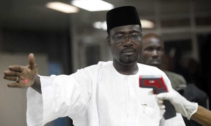 Oficial usa termômetro em passageiro na entrada do aeroporto Murtala Muhammed em Lagos, na Nigéria, em foto de 6 de agosto