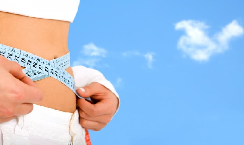 Imagem ilustrativa: mulher medindo a cintura em processo de emagrcimento.