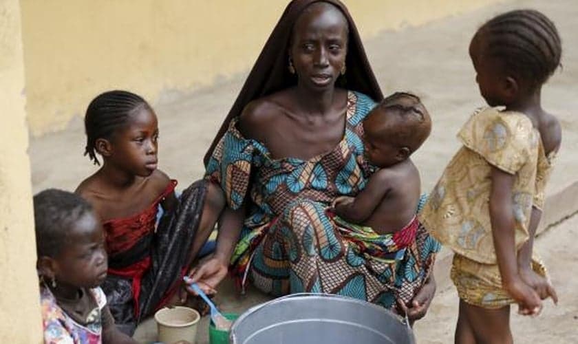 Mulher resgatada dos domínios do Boko Haram pelo exército nigeriano alimenta seus filhos em acampamento para refugiados