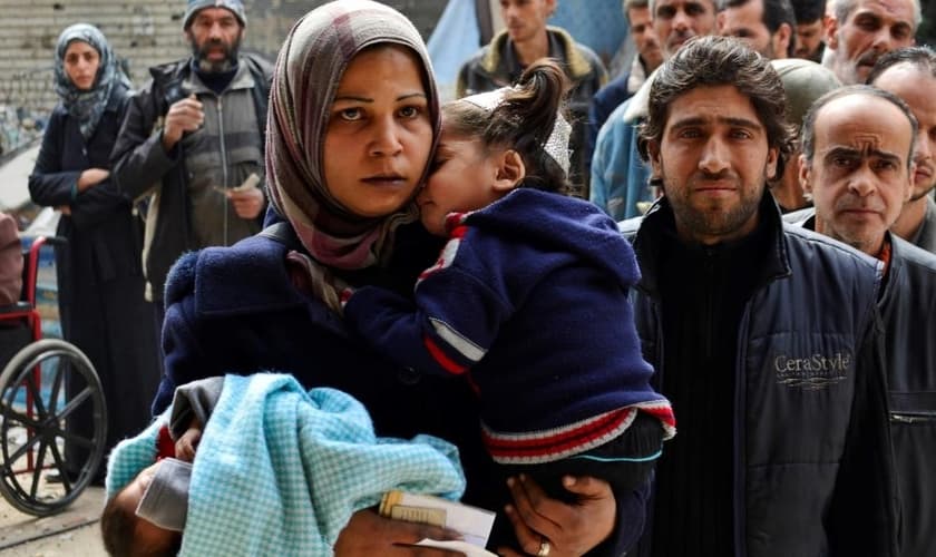 Pessoas fazem fila para receber ajuda humanitária no campo de refugiados palestinos.