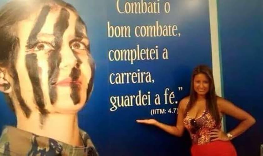 Drielle diante de mural com versículo: "Combati o bom combate, completei a carreira, guardei a fé". (Jornal Atual Rio)