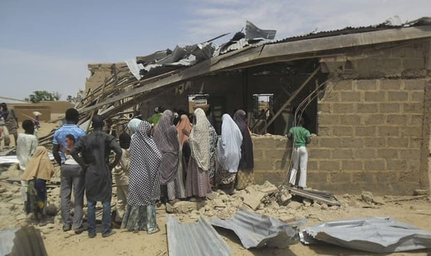 Pessoas são vistas ao redor de igreja que foi alvo de ataque suicida. (Foto: Adamu Adamu/AP)