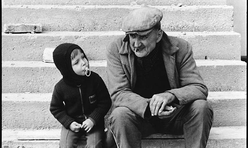Idoso conversa com garoto.