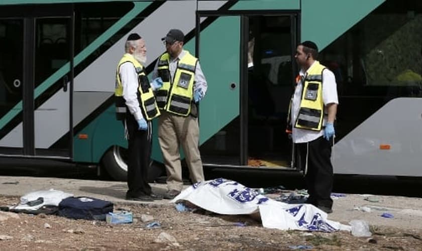 Forças de segurança israelenses conversam ao lado de corpo após ataque a tiros contra um ônibus próximo ao bairro palestino de Jabal Mukaber, em Jerusalém Oriental. (Foto: Thomas Coex/AFP)