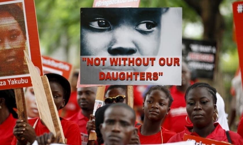 Familiares e amigos participam de manifestação, clamando pelo resgate das meninas sequestradas pelo Boko Haram em 2014, segurando placas como esta, que diz "Não sem nossas filhas"e com o lema "Tragam nossas garotas de volta" (Foto: Reuters)