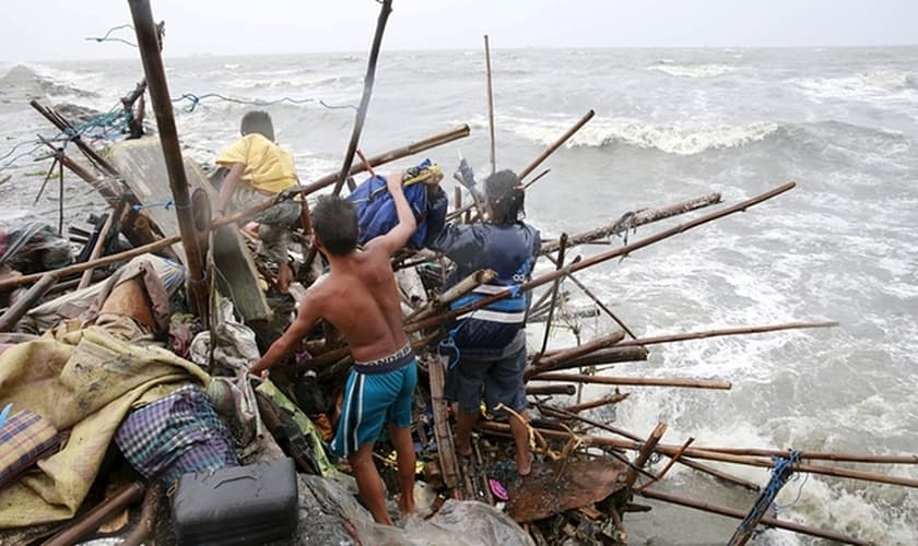 Uma família que vive na baía de Manila tenta achar pertences que possam ser recuperados, após a sua casa ter sido destruída por fortes ventos trazidos pelo tufão Koppu neste domingo, 18/10. (Foto: Romeo Ranoco/Reuters)