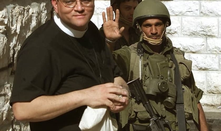 Um soldado israelense (R) recebe o Rev. Andrew White, o "vigário de Bagdá", enquanto ele tenta visita a Igreja da Natividade, em Belém, no dia 14 de abril de 2002. (Foto: Reuters/Oleg Popov)