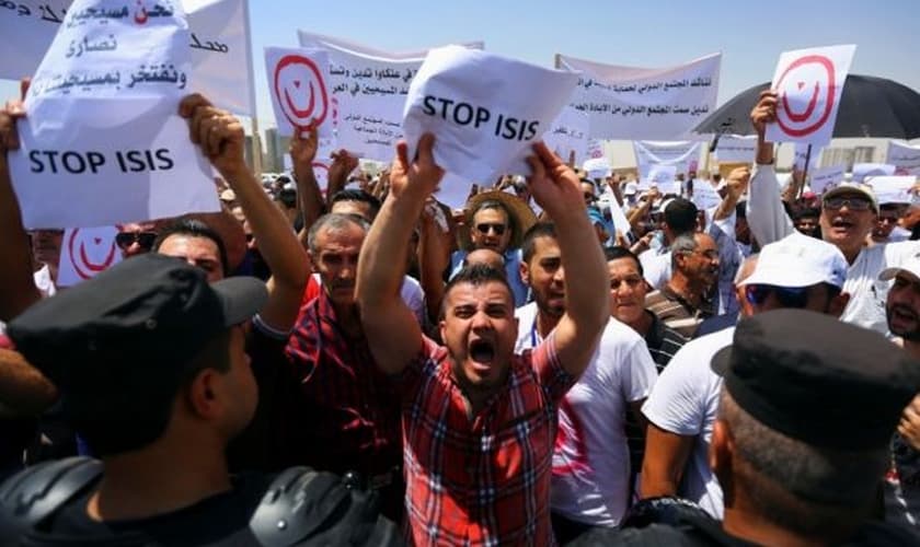 Cidadãos iraquianos seguram cartazes e placas durante protesto contra ações do Estado Islâmico, em 2014. (Foto: Reuters/Stringer)