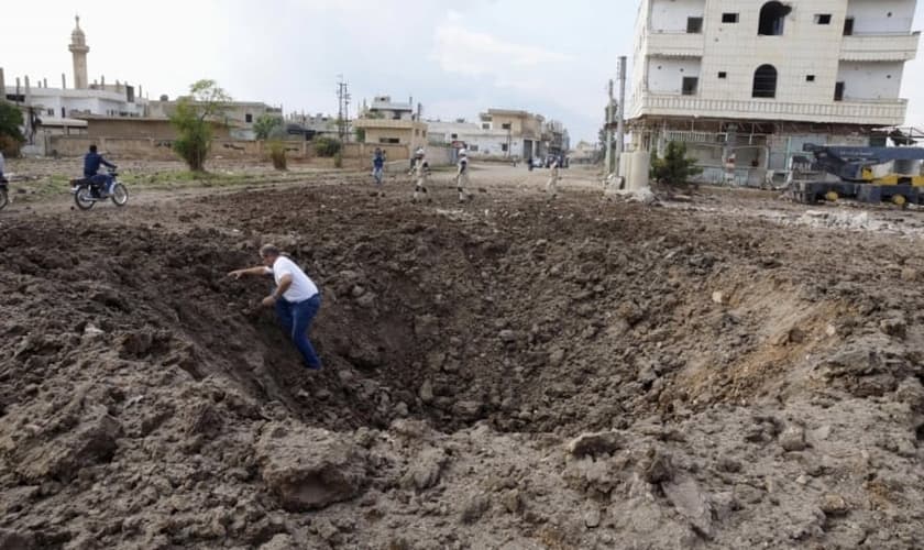 Homem sai de uma cratera causada pelo que, segundo ativistas, foi aberta pelo lançamento de bombas das forças leais ao presidente da Síria, Bashar Al-Assad. (Foto: Reuters)