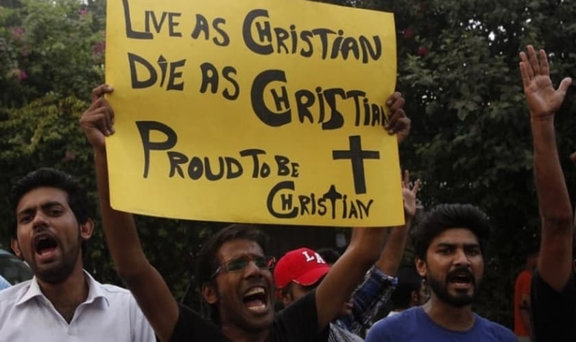 Manifestante paquistanês segura cartaz com as frases: "Viver como cristão! Morrer como cristão! Orgulho de ser cristão!". (Foto: Reuters)