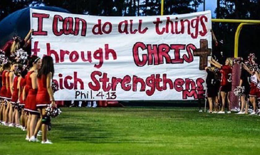 "Tudo posso naquele que me fortalece (Filipenses 4:13)" é a mensagem que o cartaz das animadoras de torcida carrega. (Foto: Liberty Institute)
