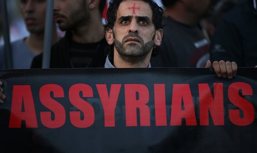 Um homem assírio caminha durante um protesto unido a centenas de pessoas. (Foto: Reprodução/The Wall Street Journal)