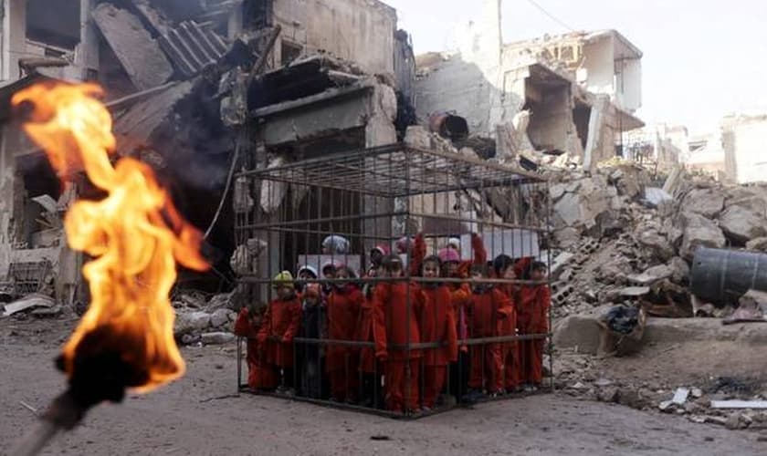 Militante segura uma tocha acesa próximo a crianças presas em uma gaiola em Damasco. (Foto: Reuters/Bassam Khabieh)