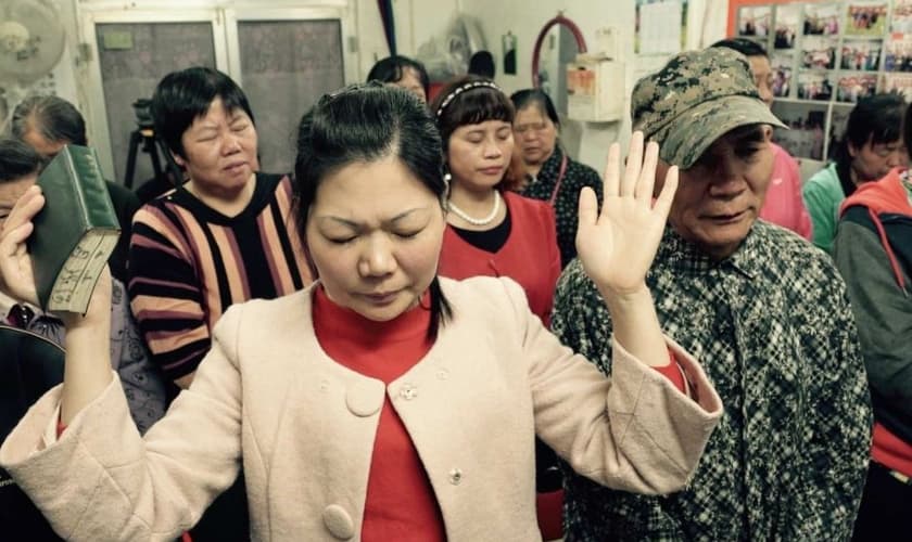 Cristãos em oração numa pequena igreja subterrânea que acontece numa loja em Pequim, na China. (Foto: Wayne Mcallister)